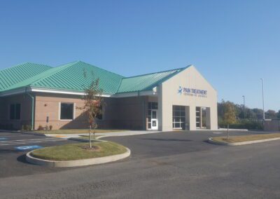 A building with a green roof and a parking lot.