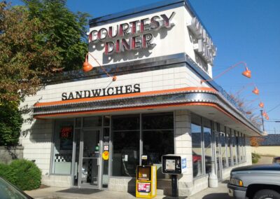 A parked car in front of a sandwich shop.